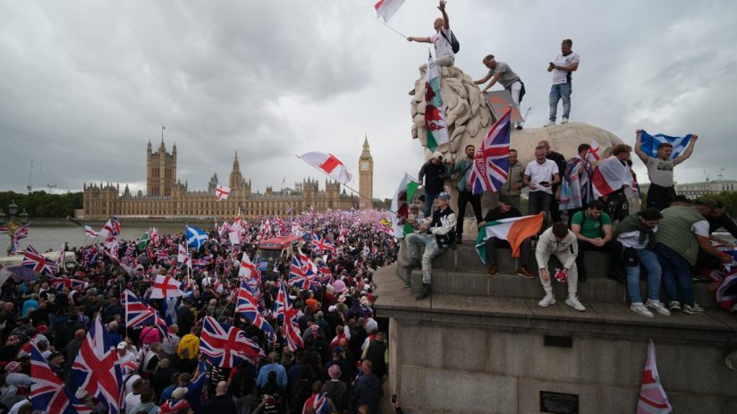 Crowd gathers in London for Unite the Kingdom rally, holding banners and flags, advocating for national unity and solidarity.