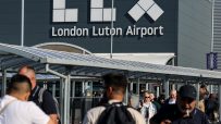 Luton Airport aerial view with planes, runways, and terminal buildings, highlighting busy travel hub operations
