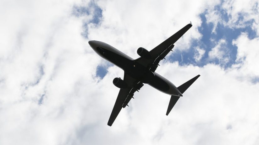 Commercial airplane flying in clear blue sky, representing aviation news and current trends in the airline industry.
