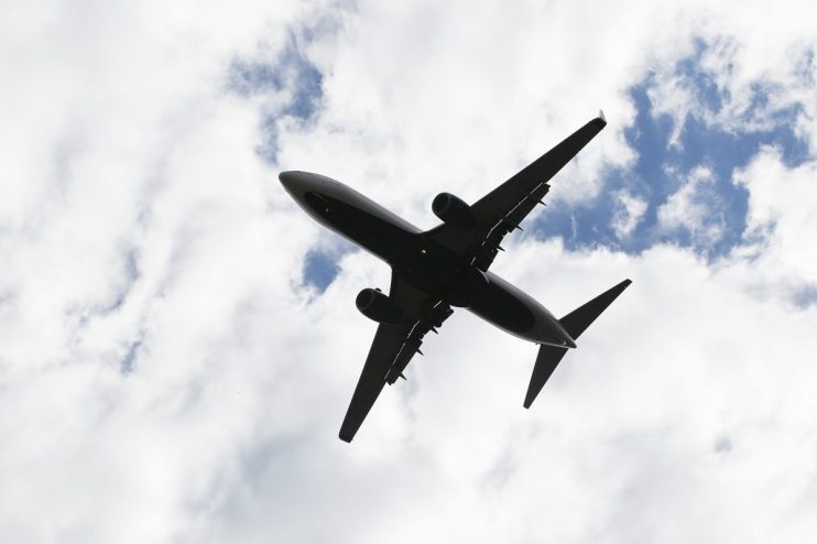 Commercial airplane flying in clear blue sky, representing aviation news and current trends in the airline industry.