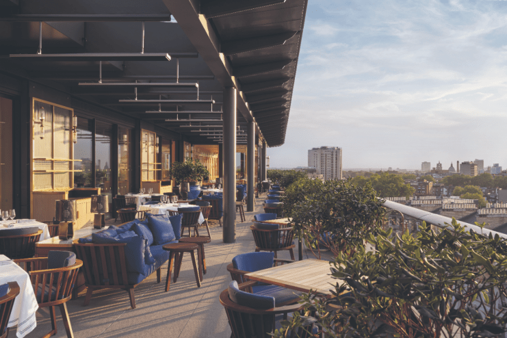 London skyline view from a rooftop bar in Kensington and Chelsea, featuring stylish seating and vibrant evening atmosphere