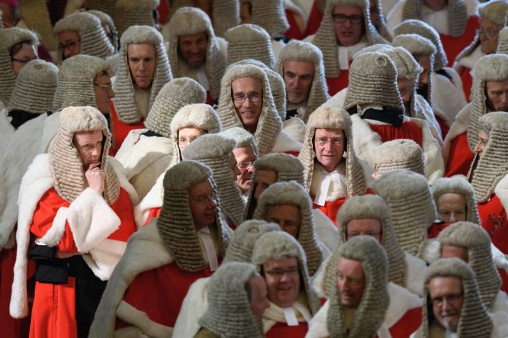 UK court judges in traditional robes and wigs seated in a courtroom, discussing important legal proceedings.