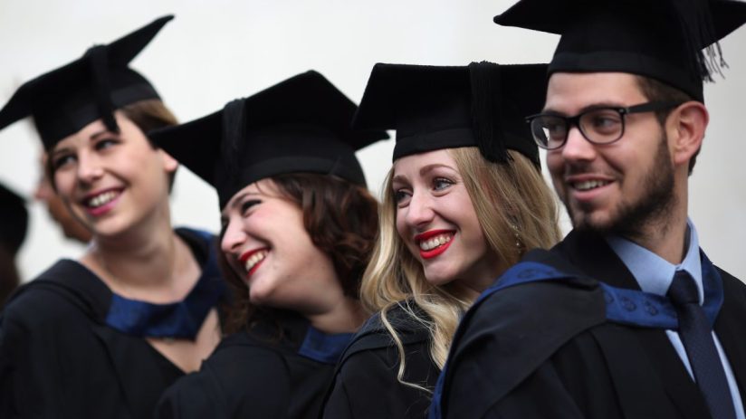 Young UK graduates from Gen Z celebrating in caps and gowns, representing the future workforce and educational achievements.