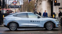Wayve autonomous vehicle navigating a busy London street with iconic cityscape in the background