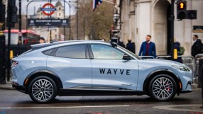 Wayve autonomous vehicle navigating a busy London street with iconic cityscape in the background