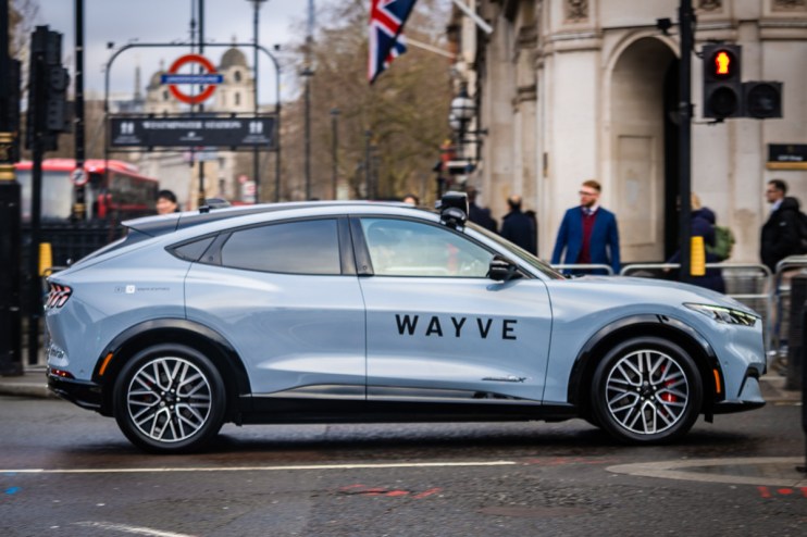 Wayve autonomous vehicle navigating a busy London street with iconic cityscape in the background