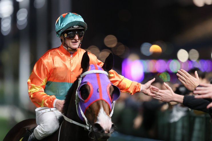 Zac Purton in a dynamic pose during a horse racing event, showcasing skill and concentration on the racetrack