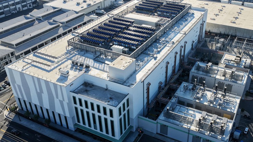 Modern data centre with rows of server racks, advanced cooling systems, and high-tech equipment under ambient lighting.