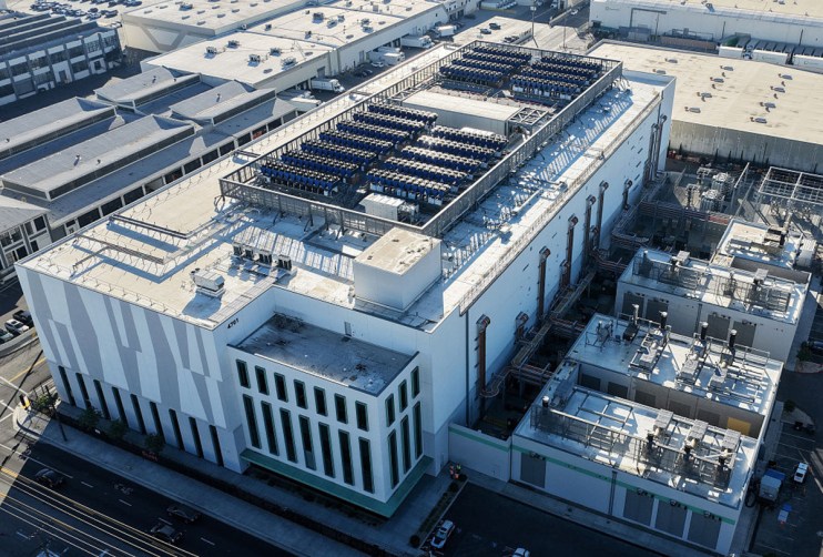 Modern data centre with rows of server racks, advanced cooling systems, and high-tech equipment under ambient lighting.
