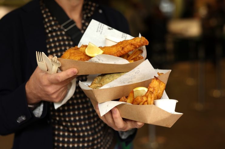 Crispy golden fish and chips served on a newspaper with lemon wedges and tartar sauce in a traditional British setting