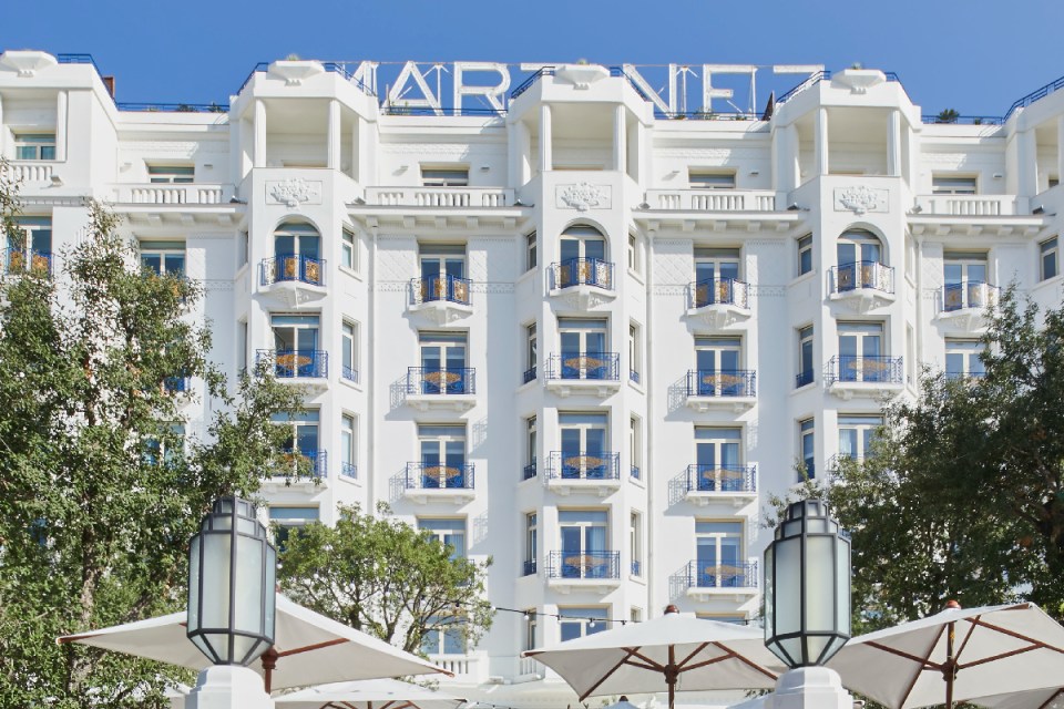 Luxurious hotel exterior in Cannes with elegant architecture and palm-lined entrance, perfect for a glamorous getaway