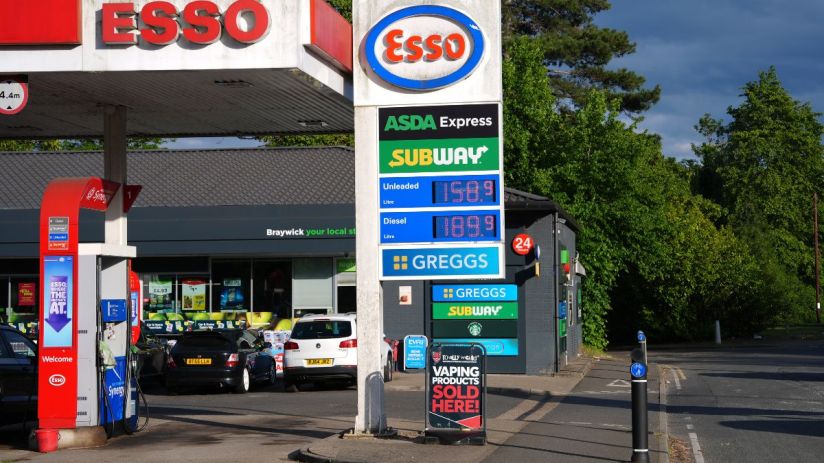 Close-up of a petrol pump nozzle dispensing fuel at a gas station, highlighting rising fuel costs and economic impact.