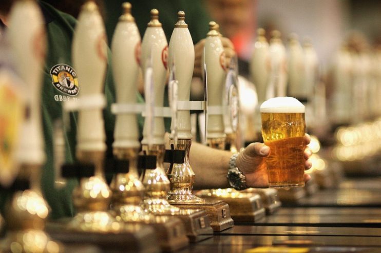 A full pint of beer with frothy head on a wooden bar counter, illuminated by soft ambient lighting in a cozy pub setting