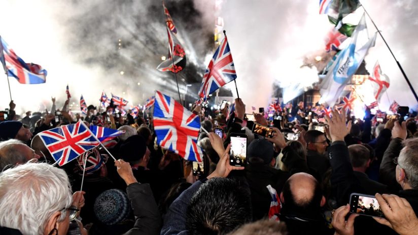 Brexit Leave party gathering with attendees holding Union Jack flags, highlighting the political atmosphere post-Brexit.
