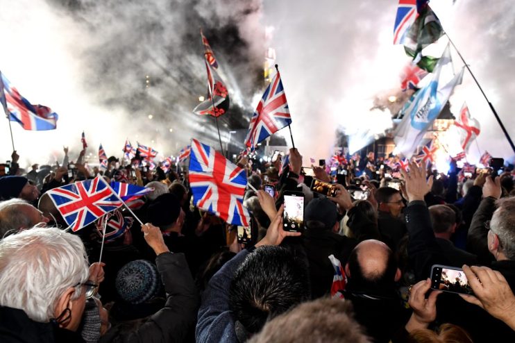 Brexit Leave party gathering with attendees holding Union Jack flags, highlighting the political atmosphere post-Brexit.