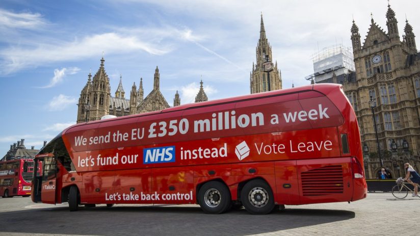 Red bus with Brexit misinformation slogan parked on a street, highlighting controversial political claims and public react...