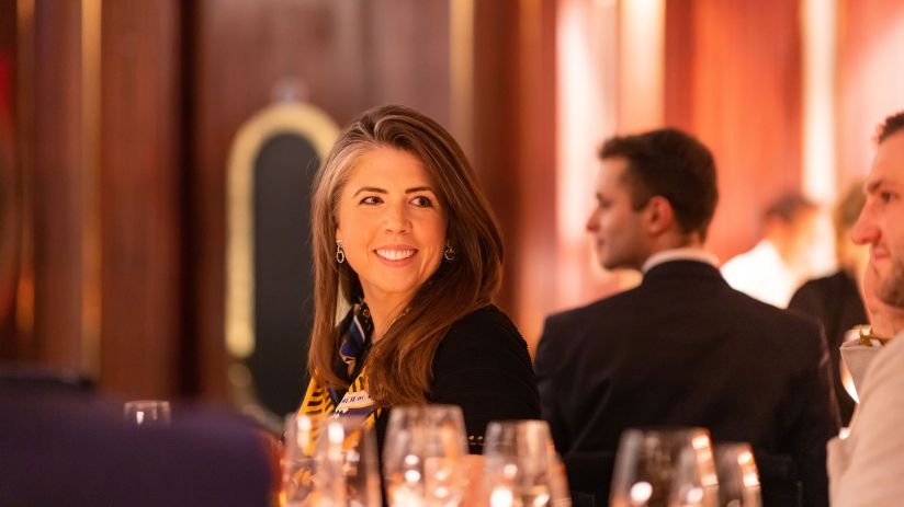 Carrie Osman, business strategist, speaking at a conference with a focused audience in a modern, well-lit venue.