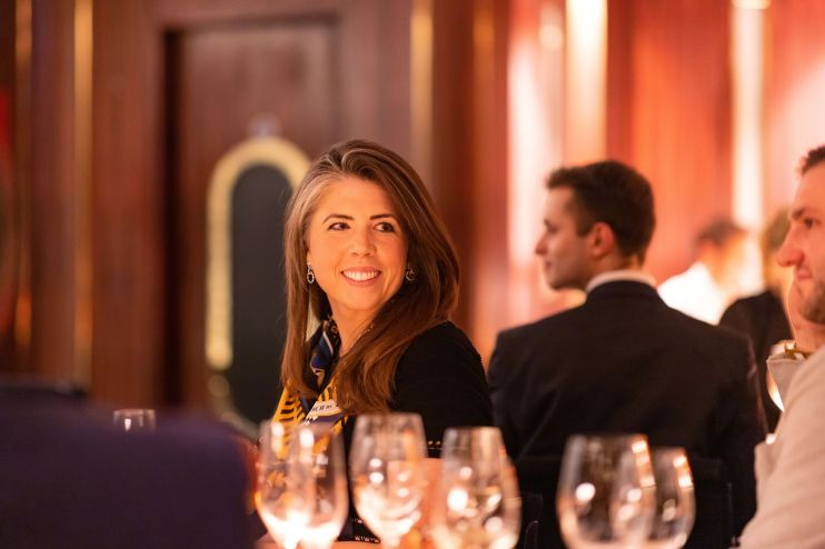 Carrie Osman, business strategist, speaking at a conference with a focused audience in a modern, well-lit venue.