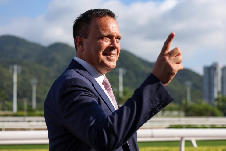 Caspar Fownes confidently poses at a racing event, showcasing his expertise and leadership in the horse racing industry.
