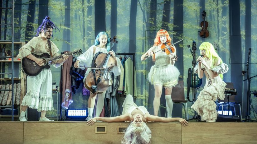 Cast of A Midsummer Nights Dream on stage, vibrant costumes, expressive poses, credit to photographer Marc Brenner