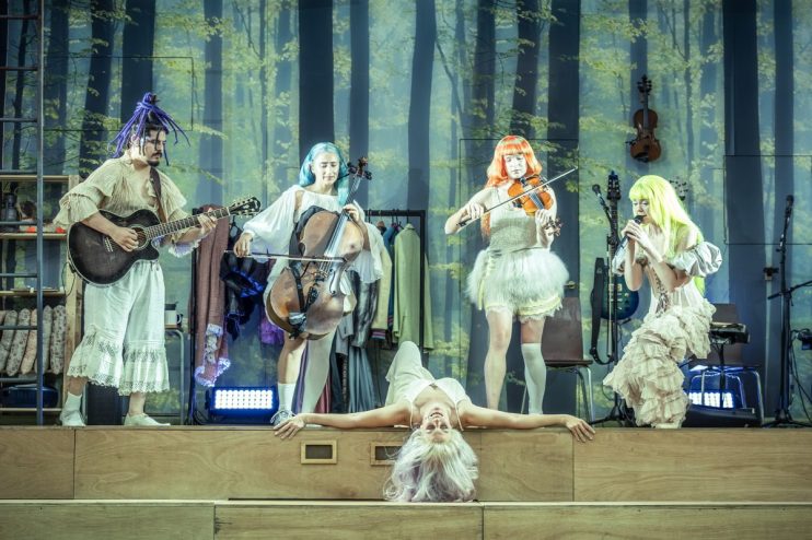 Cast of A Midsummer Nights Dream on stage, vibrant costumes, expressive poses, credit to photographer Marc Brenner