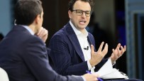 Dario Amodei, CEO of Anthropic, speaking at a tech conference podium, wearing a suit and addressing the audience.