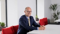 David Sleath, Chief Executive Officer, delivering a speech at a business conference with a focused expression.