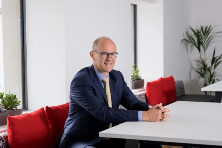 David Sleath, Chief Executive Officer, delivering a speech at a business conference with a focused expression.