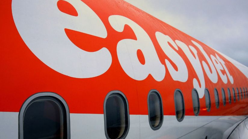 EasyJet airplane at airport terminal with passengers boarding, representing airline industry and travel news updates