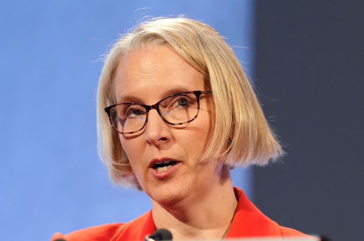 Emma Reynolds speaking at a business conference podium, engaging audience with insights on industry trends and strategies.
