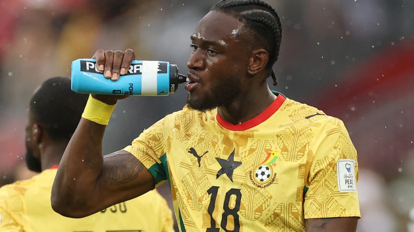 Football players taking a hydration break during a World Cup match, highlighting the divisive pause amid rising temperatures.