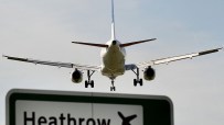 Commercial airplane landing at Heathrow Airport, seen from behind, with a prominent Heathrow sign below.