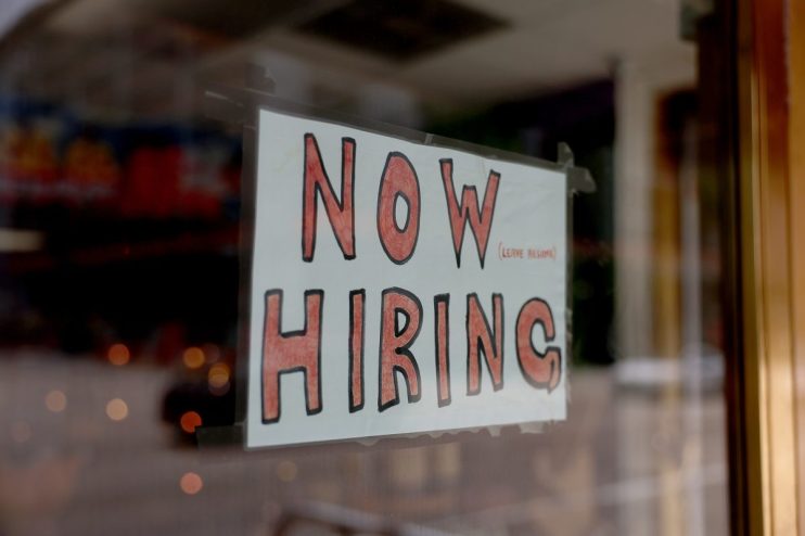 Prominent hiring sign displayed in front of a business, indicating job vacancies and employment opportunities