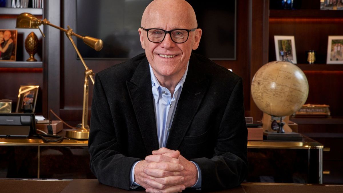 John Caudwell in a formal setting, possibly during a business meeting or public speaking event, conveying professionalism.
