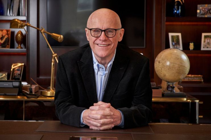 John Caudwell in a formal setting, possibly during a business meeting or public speaking event, conveying professionalism.