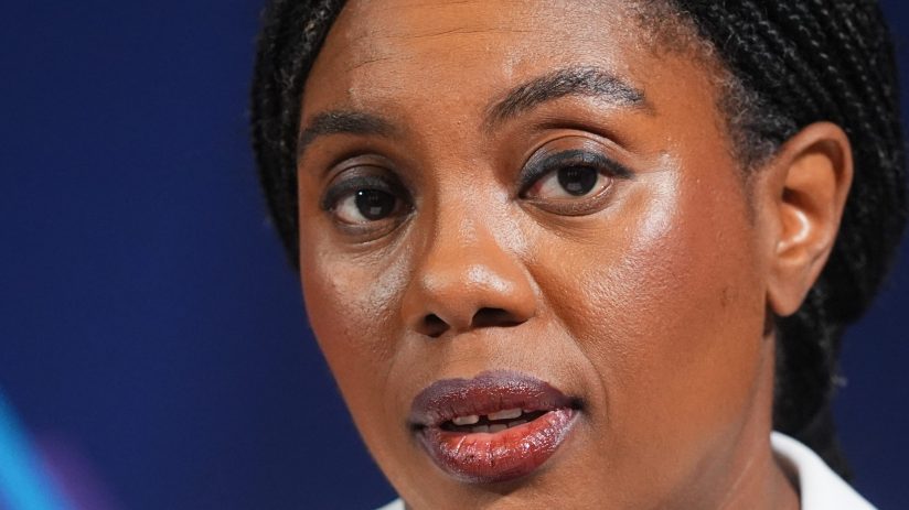 Kemi Badenoch speaking at a podium during a press conference, addressing recent policy changes and business initiatives.