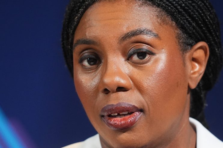 Kemi Badenoch speaking at a podium during a press conference, addressing recent policy changes and business initiatives.
