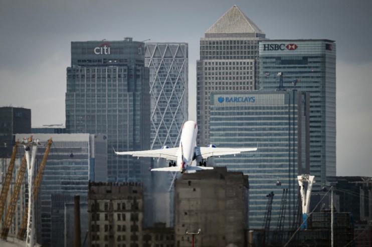 London City Airport terminal bustling with travelers and staff, showcasing modern architecture and vibrant city backdrop.