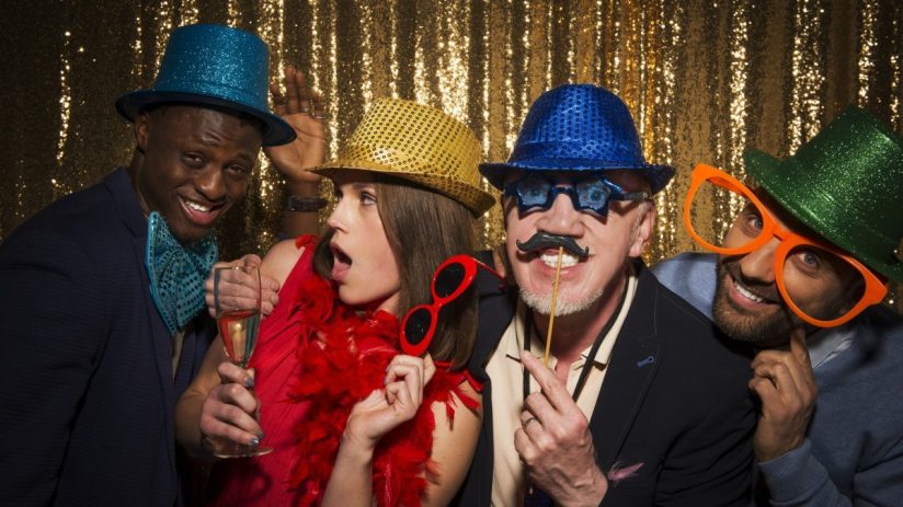 Friends taking photobooth selfies at a lively event, capturing joyful expressions and playful poses in a casual setting.