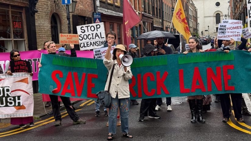 Protesters rally at Brick Lane holding signs to oppose a data centre development plan, highlighting community concerns.