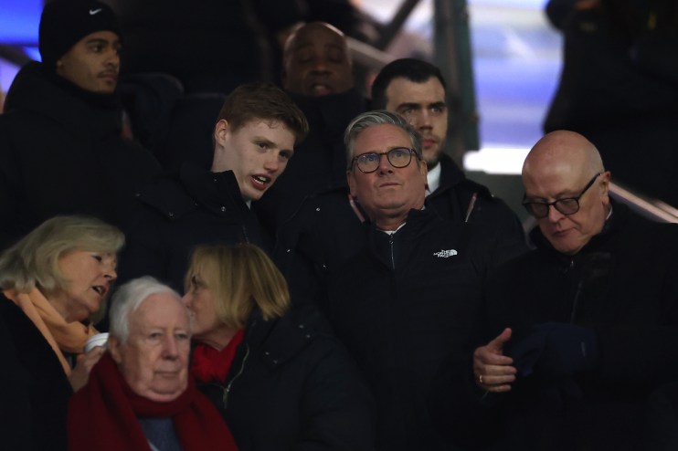 Keir Starmer visits Arsenal football ground, engaging in discussions with fans and officials in a vibrant stadium setting.