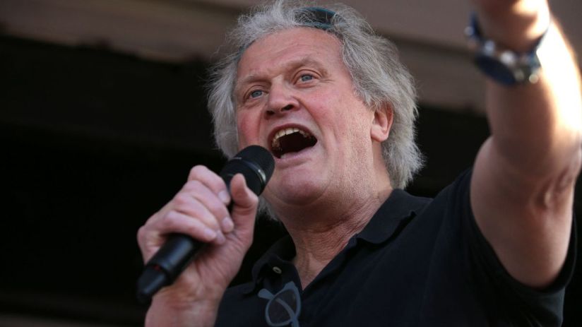 Tim Martin speaking at a business conference podium dressed in a suit, emphasizing key industry insights and strategies.