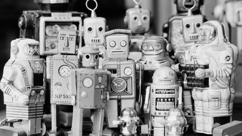Colorful vintage tin robots lined up on a shelf, showcasing intricate designs and mechanical details for a retro toy exhibit.