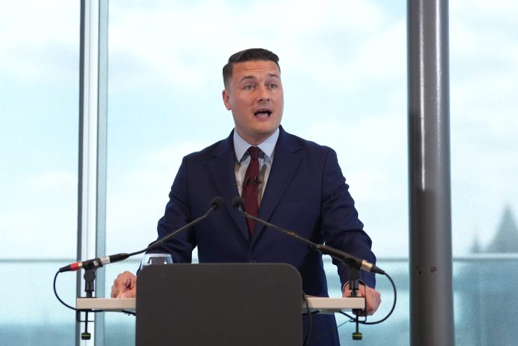 Wes Streeting, British politician, delivering a speech at a press conference with a focused expression and engaging the au...
