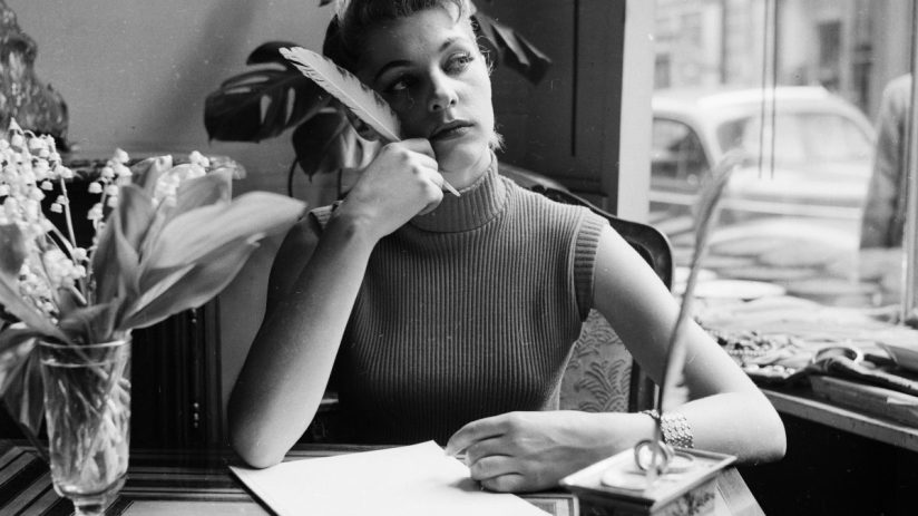 Writer working diligently at a desk, surrounded by notes and a laptop, focused on creating content for a news article.
