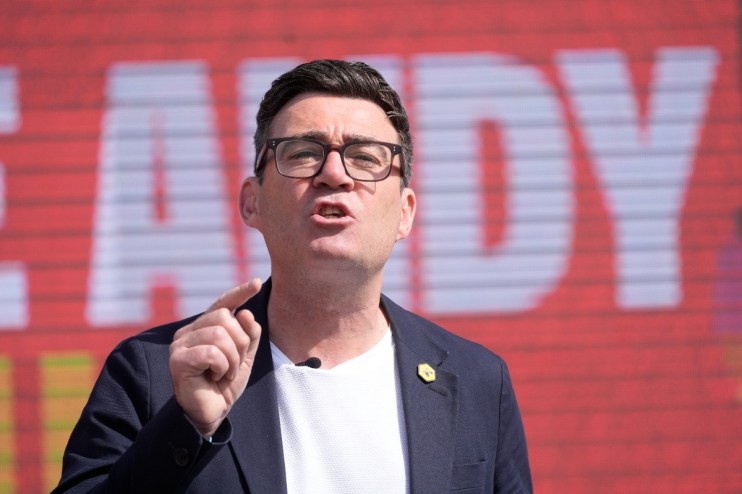 Andy Burnham addressing audience as Mayor of Greater Manchester in formal setting, wearing a suit and tie.