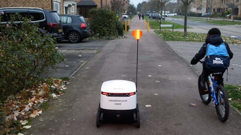 Autonomous delivery robot navigating a city pavement, showcasing innovative urban delivery technology and mobility solutions.