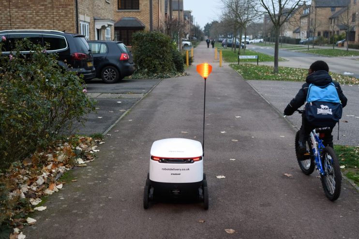 Autonomous delivery robot navigating a city pavement, showcasing innovative urban delivery technology and mobility solutions.