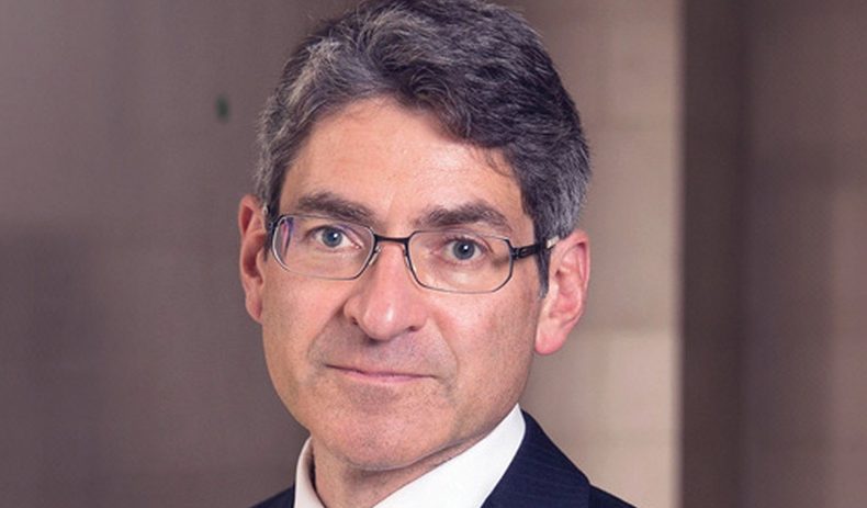Jonathan Haskel speaking at a business conference, wearing a suit and tie with a focused expression, emphasizing economic ...