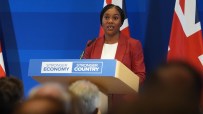 Kemi Badenoch discussing strategies for a stronger economy at a business conference podium, emphasizing economic growth